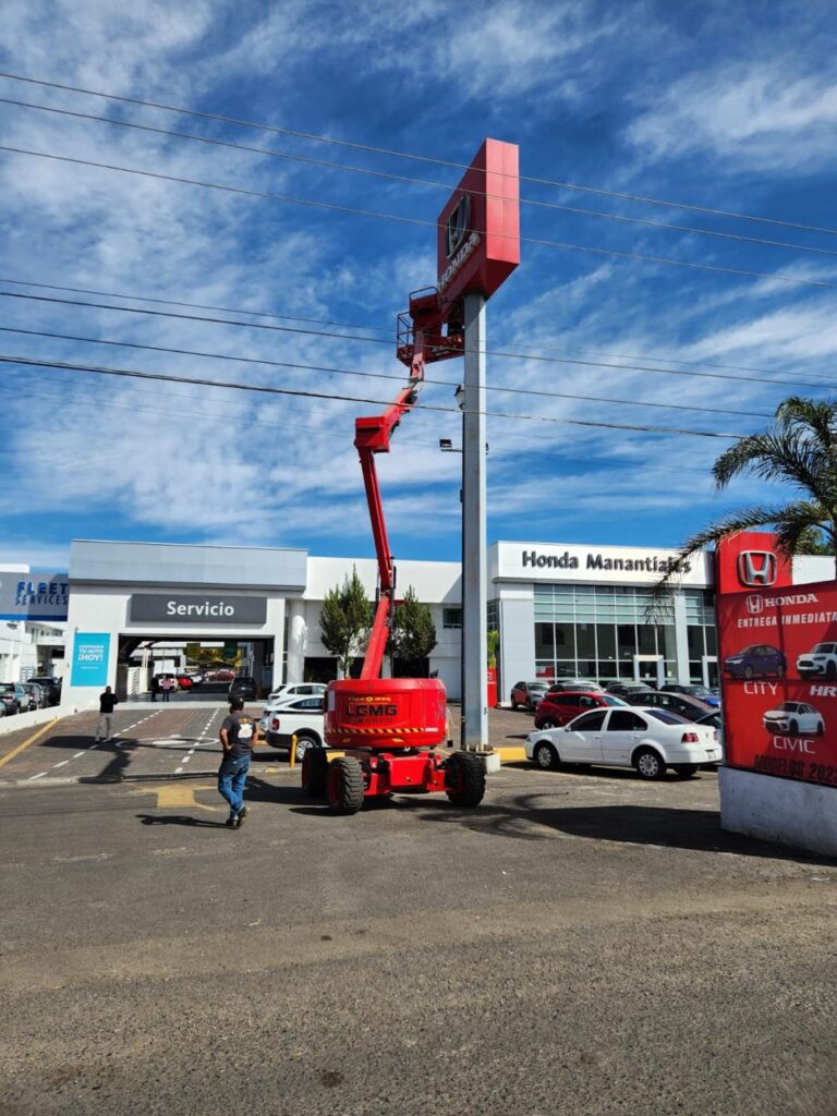 Plataformas de elevación rojas LGMG 2 Plataforma de elevacion roja de brazo en una zona pública al lado de un cartel
